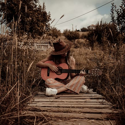 woman holding guitar sitting on dock