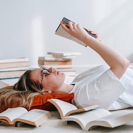 young smart woman reading book on floor