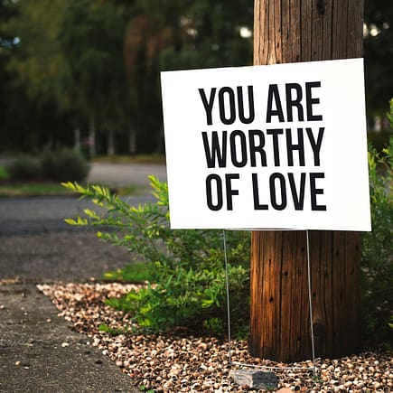 you are worthy of love signage on brown wooden post taken
