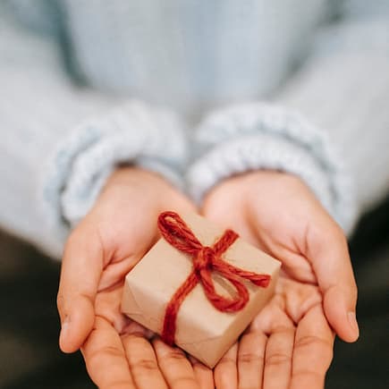 crop faceless woman showing small gift box on palms
