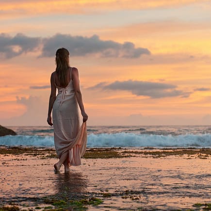 woman standing on sand near shoreline