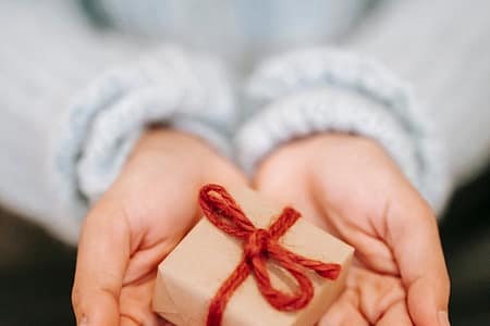 crop faceless woman showing small gift box on palms